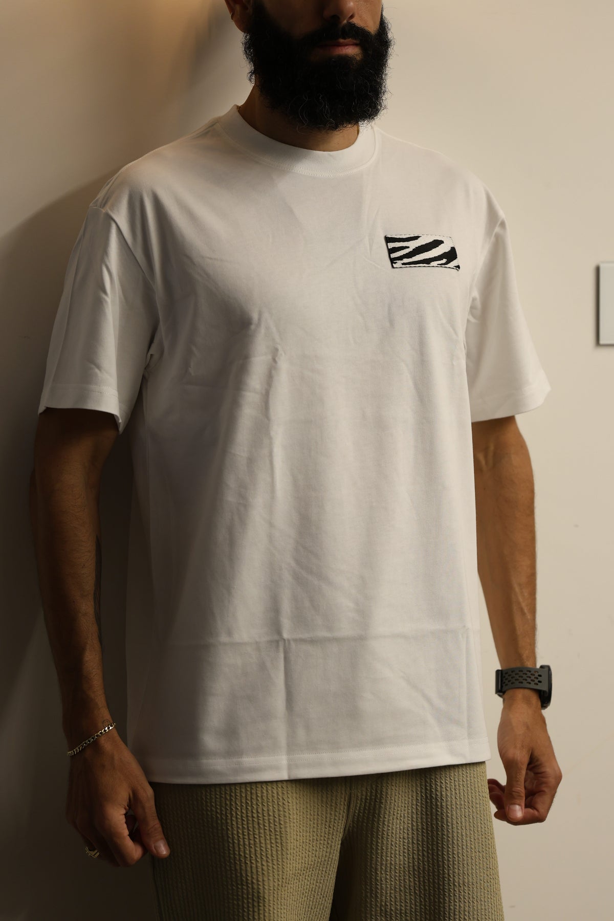 Person wearing a white t-shirt with a logo on a neutral background