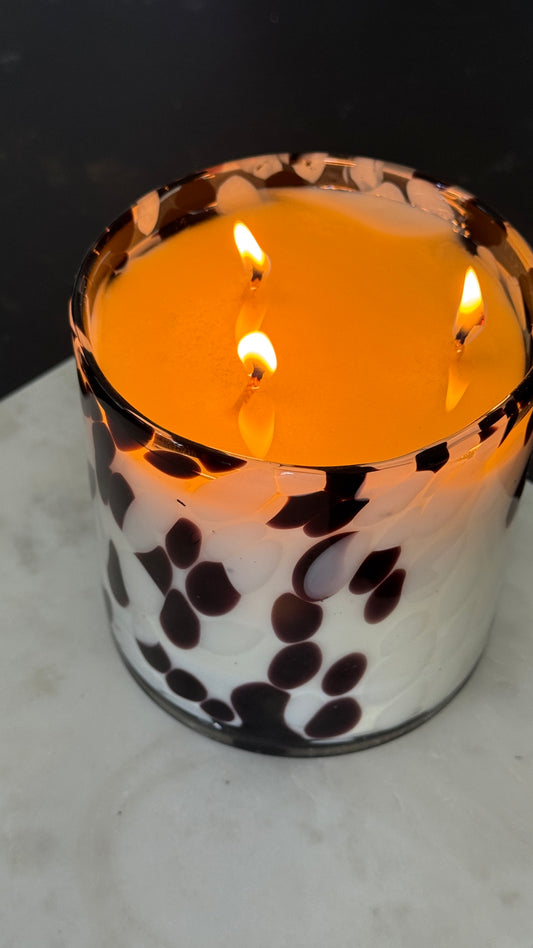 Candle in a decorative holder with a black and white pattern on a dark background