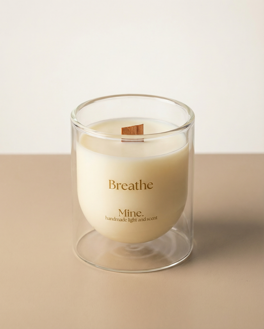 Candle in a glass holder with 'Breathe' text on a beige background
