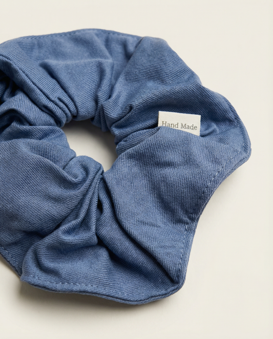 Blue scrunchie with a 'Hand Made' label on a light beige background