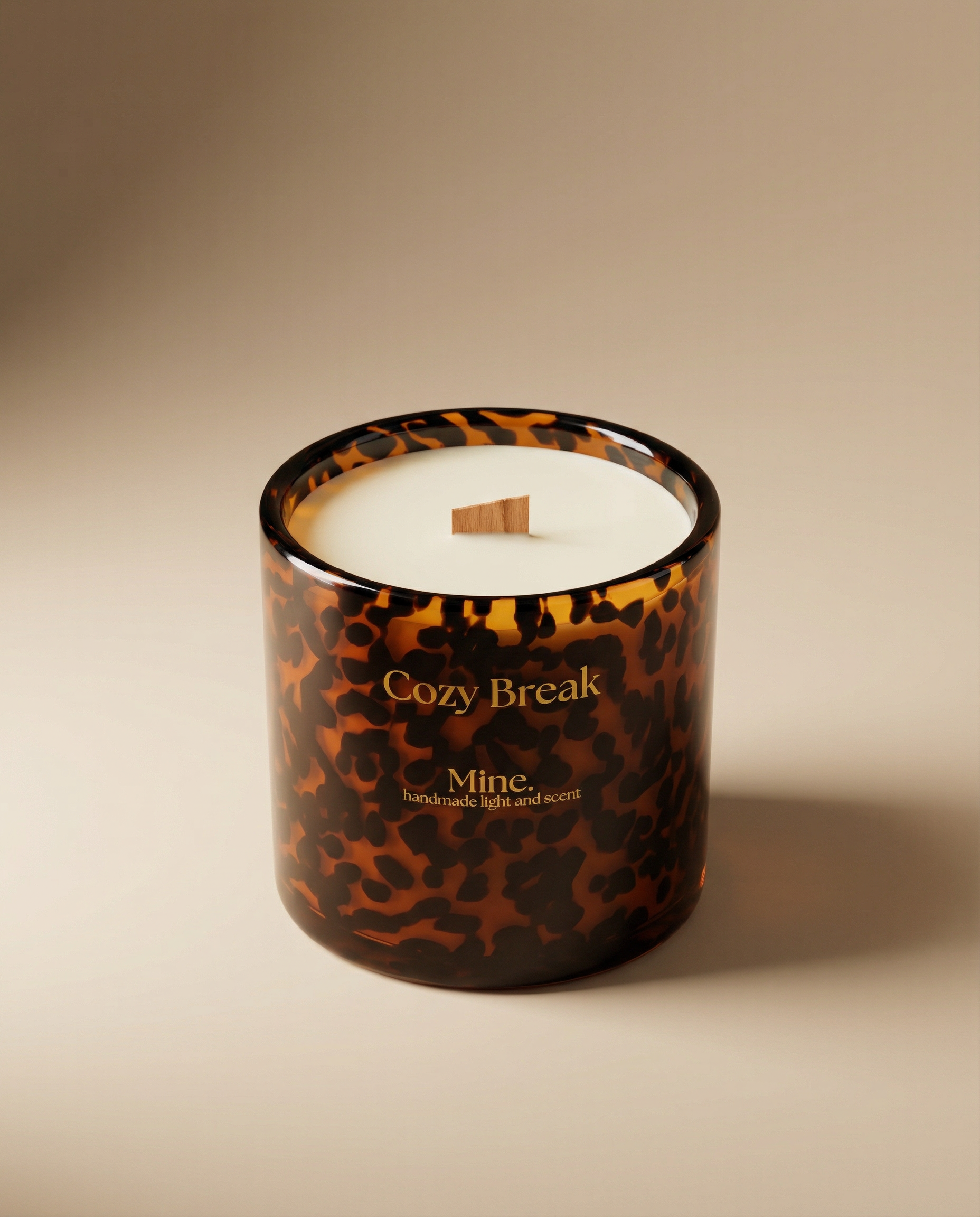 Candle with tortoiseshell pattern and 'Cozy Break' text on a beige background