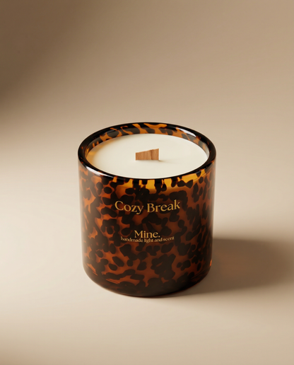 Candle with tortoiseshell pattern and 'Cozy Break' text on a beige background