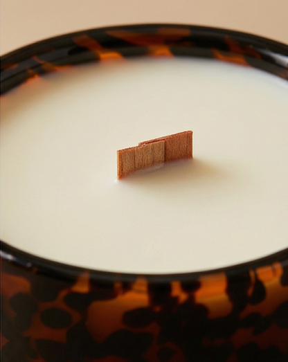 Close-up of a tortoiseshell-patterned candle with a small rectangular object on top.