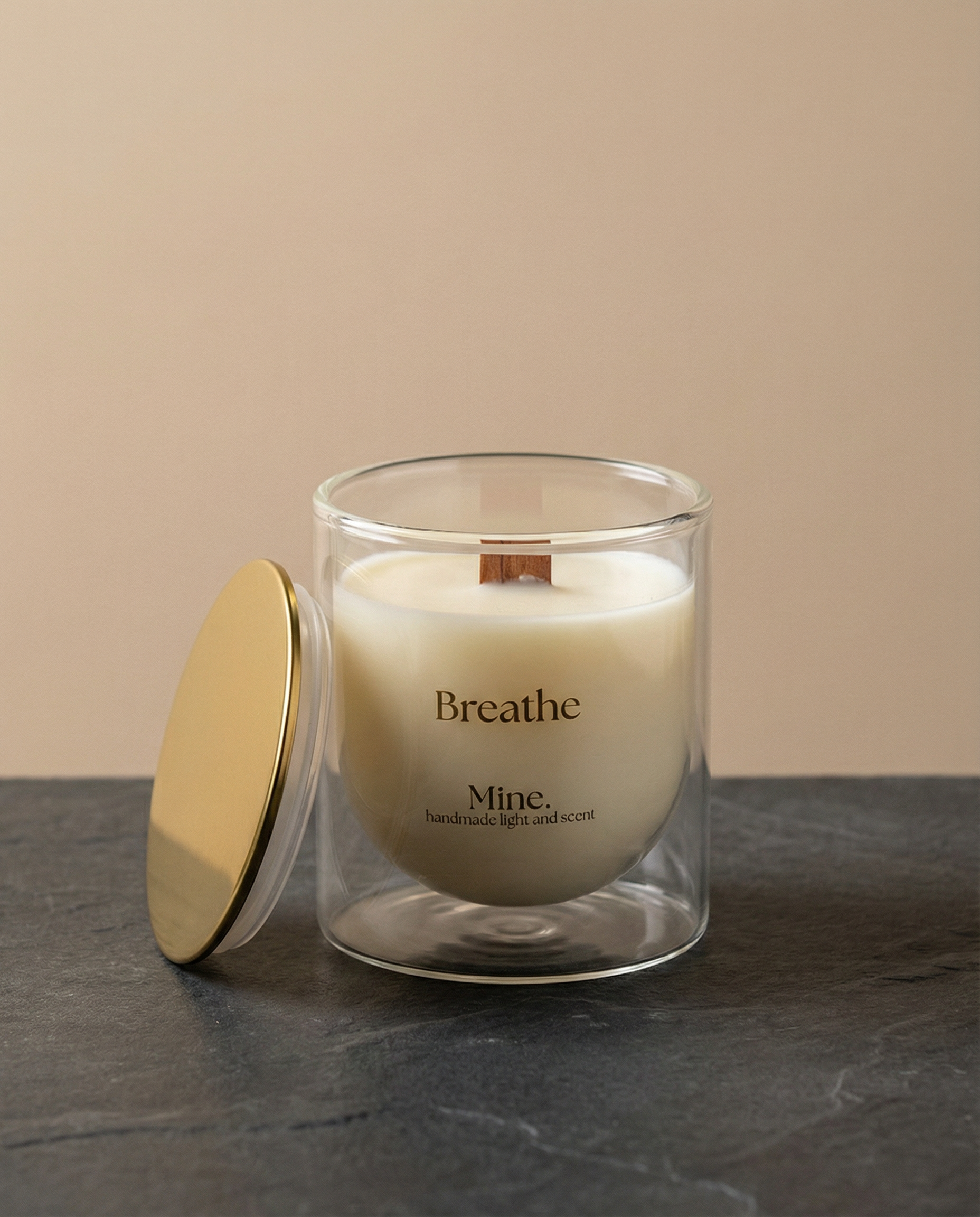 Glass candle with a gold lid on a dark surface and beige background