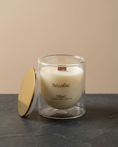 Glass candle with a gold lid on a dark surface and beige background