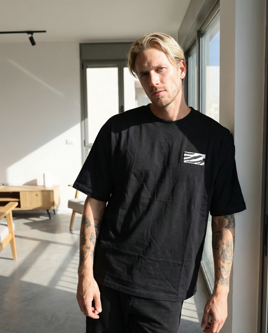 Man wearing a black t-shirt with a logo in a modern indoor setting