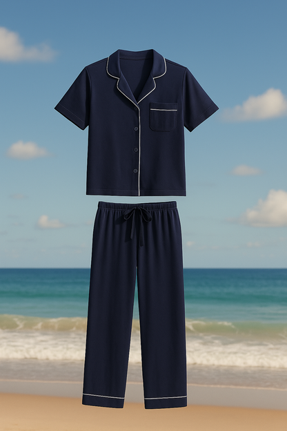 Navy blue pajama set with white piping on a beach background