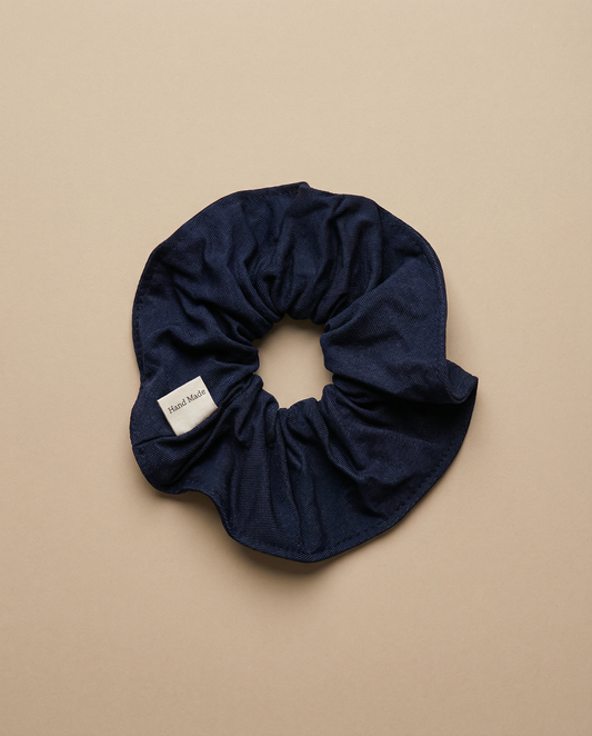 Navy blue scrunchie with a brand label on a beige background
