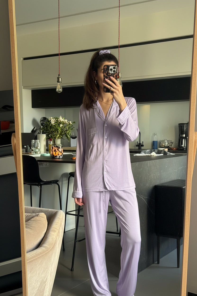 Person wearing a light purple pajama set taking a mirror selfie in a kitchen.