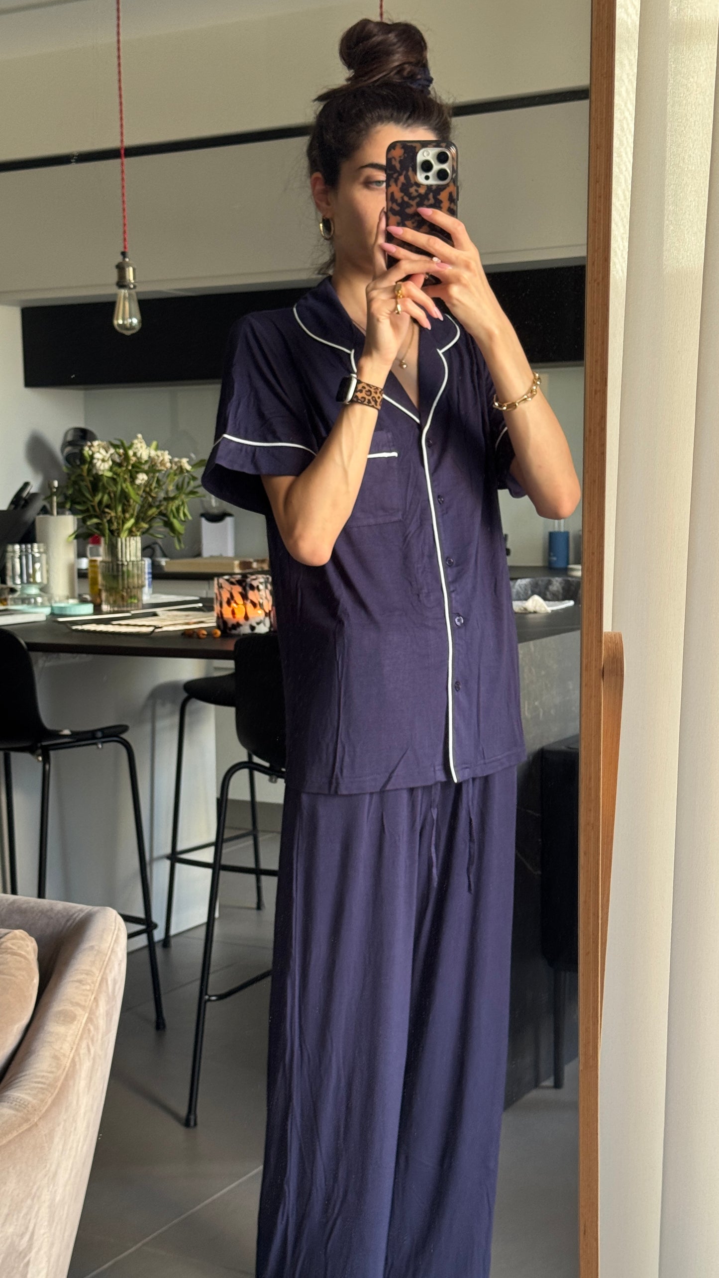 Person wearing a navy blue pajama set taking a mirror selfie in a home setting.