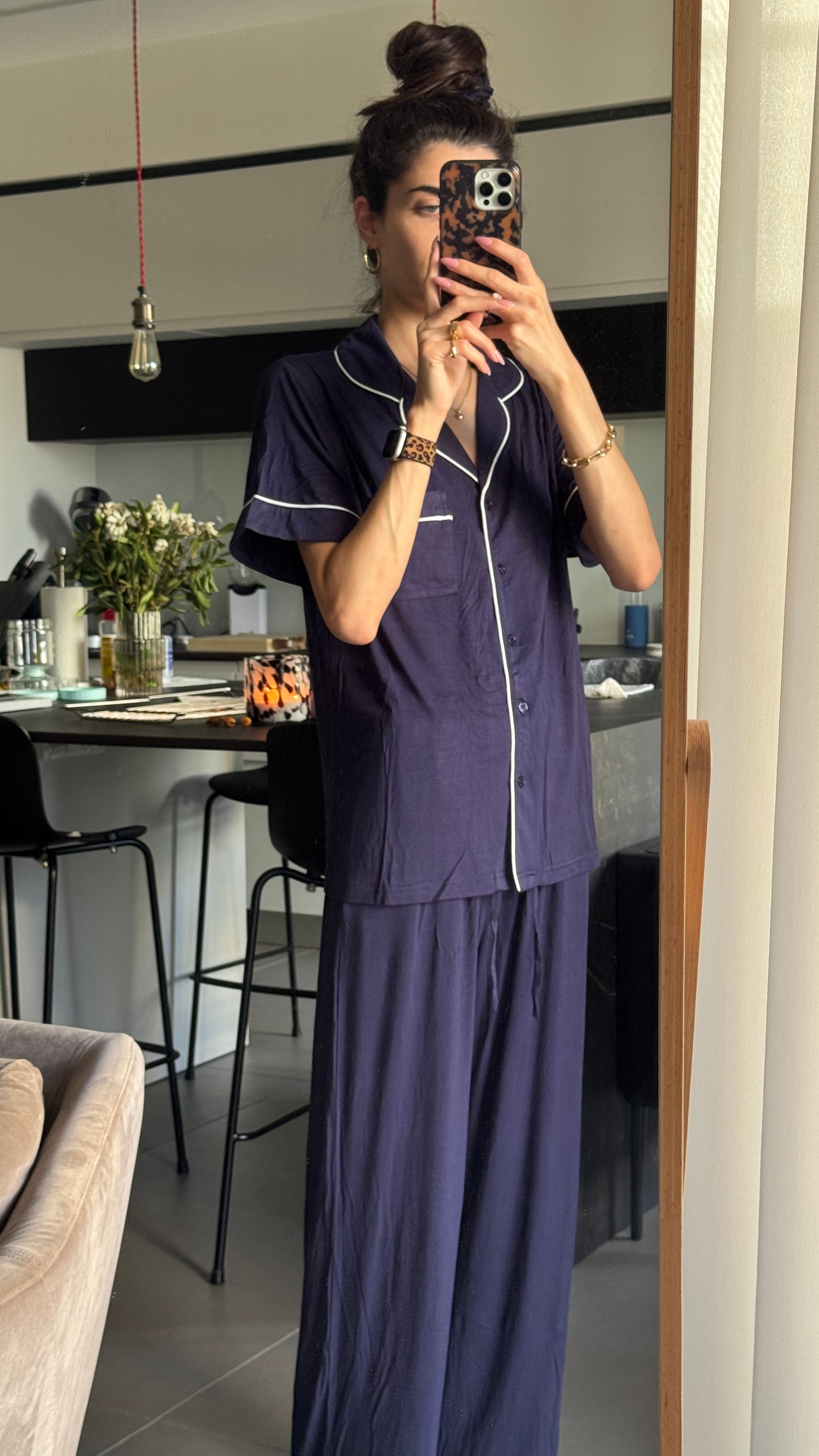 Person wearing a navy blue pajama set taking a mirror selfie in a home setting.