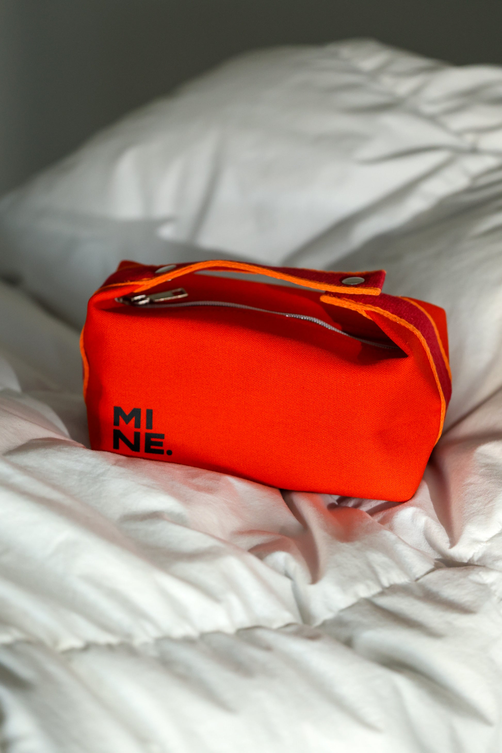 Red bag with 'MI NE' branding on a white blanket