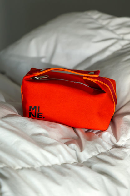 Red bag with 'MI NE' branding on a white blanket
