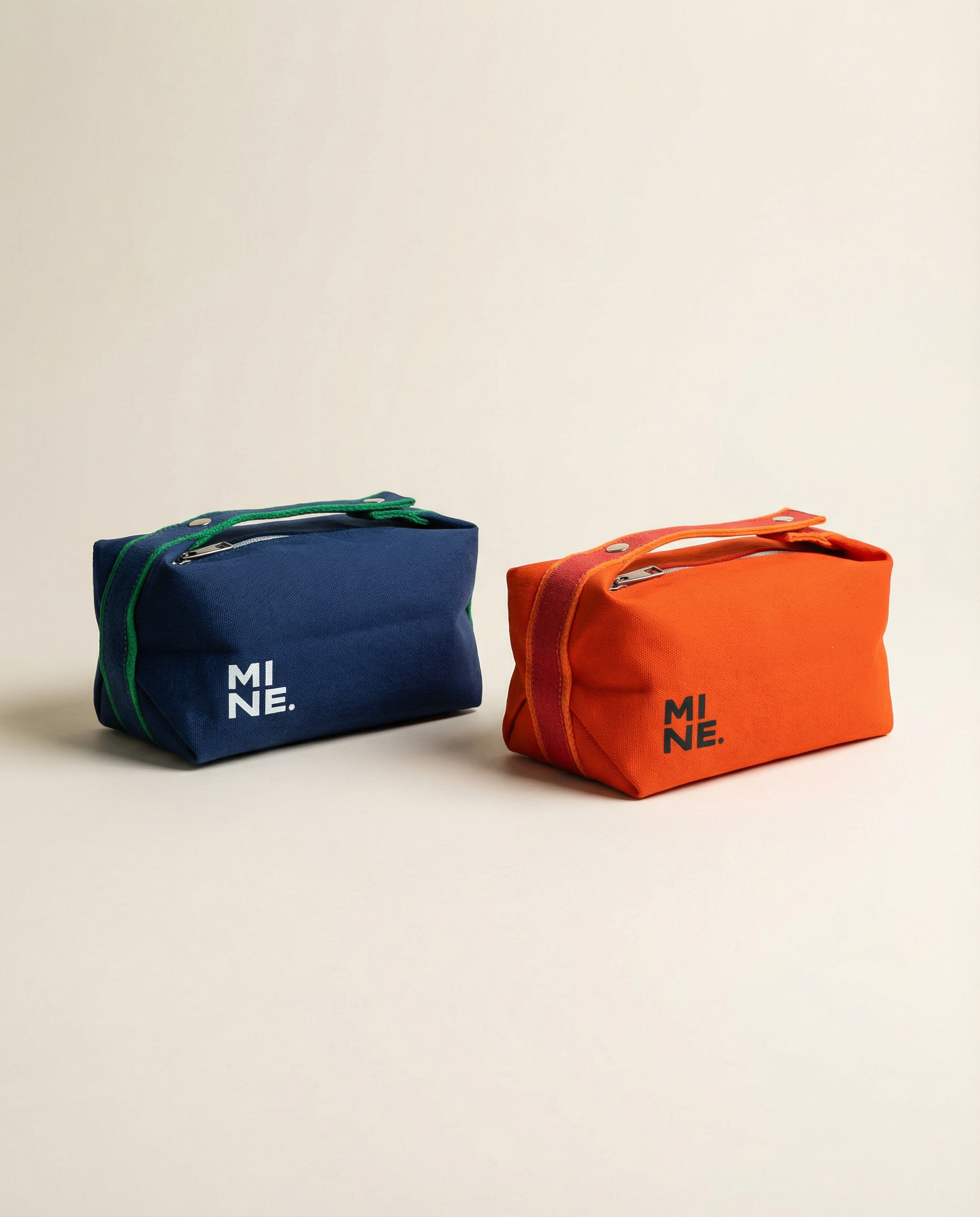 Two cosmetic bags, one blue and one orange, with 'MI NE' branding on a beige background.