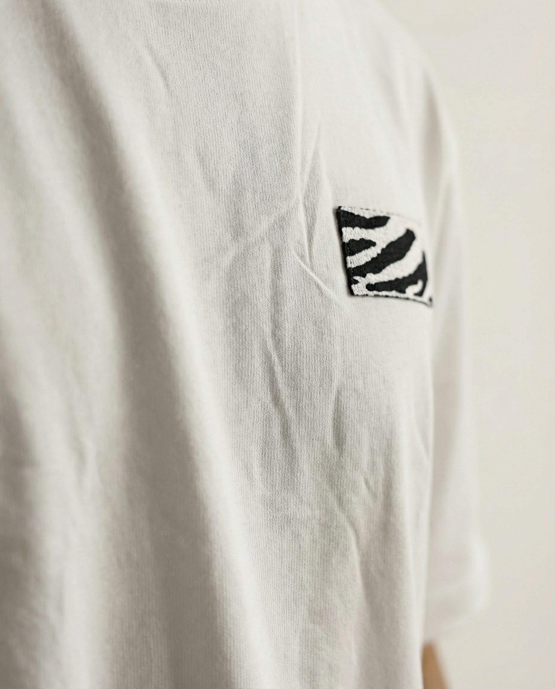 White t-shirt with a black and white zebra pattern on the chest against a beige background