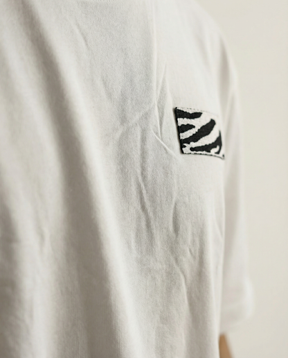 White t-shirt with a black and white zebra pattern on the chest against a beige background