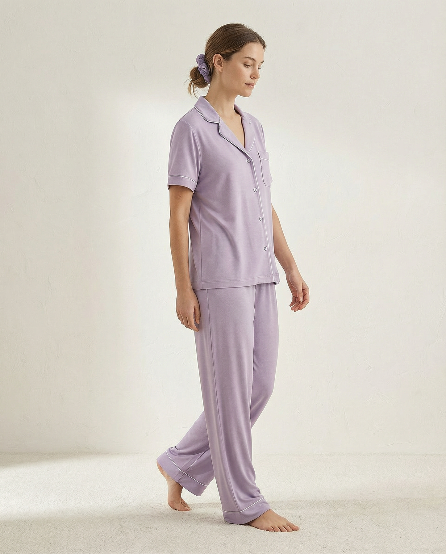 Woman wearing a lavender pajama set on a plain background