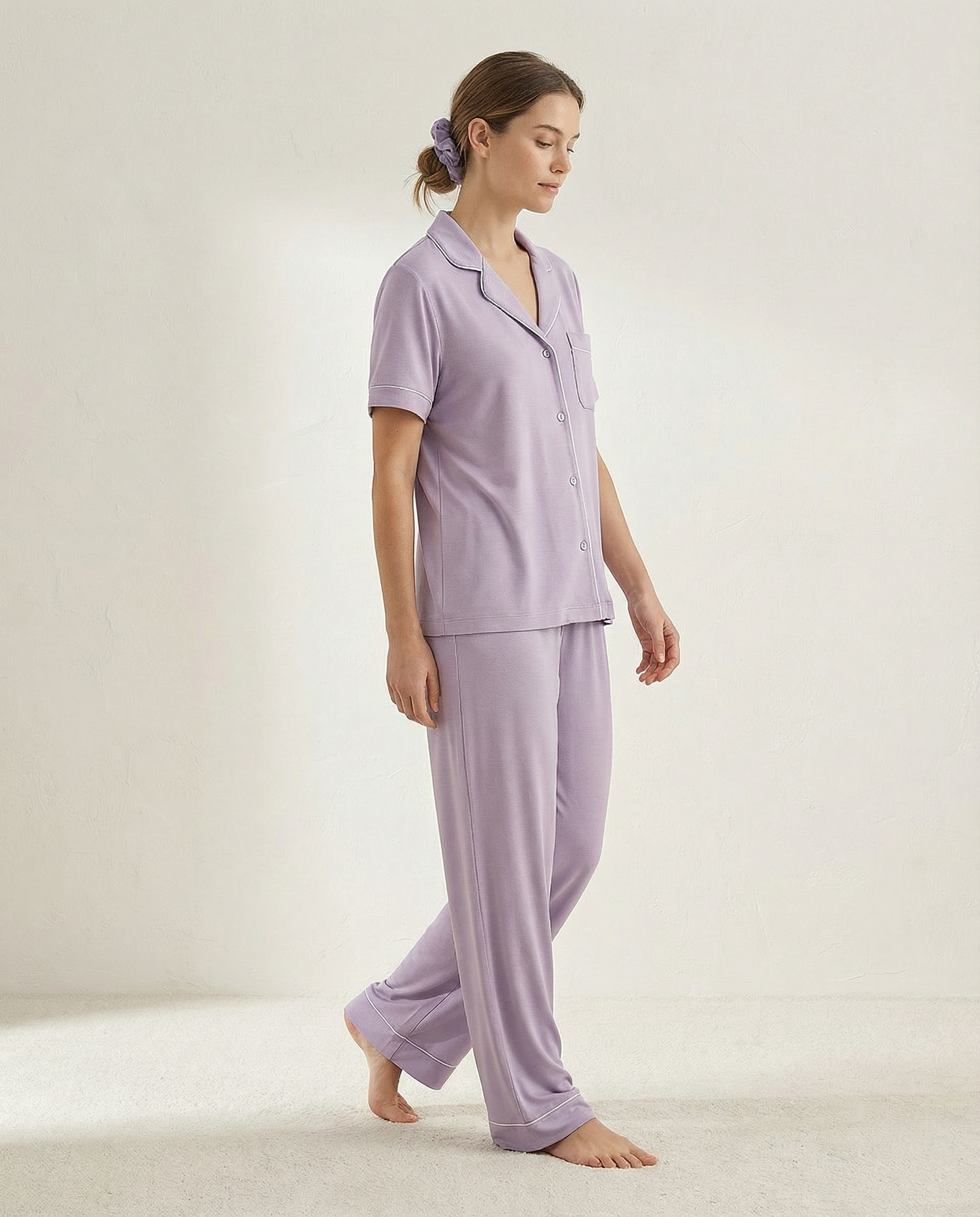 Woman wearing a lavender pajama set on a plain background