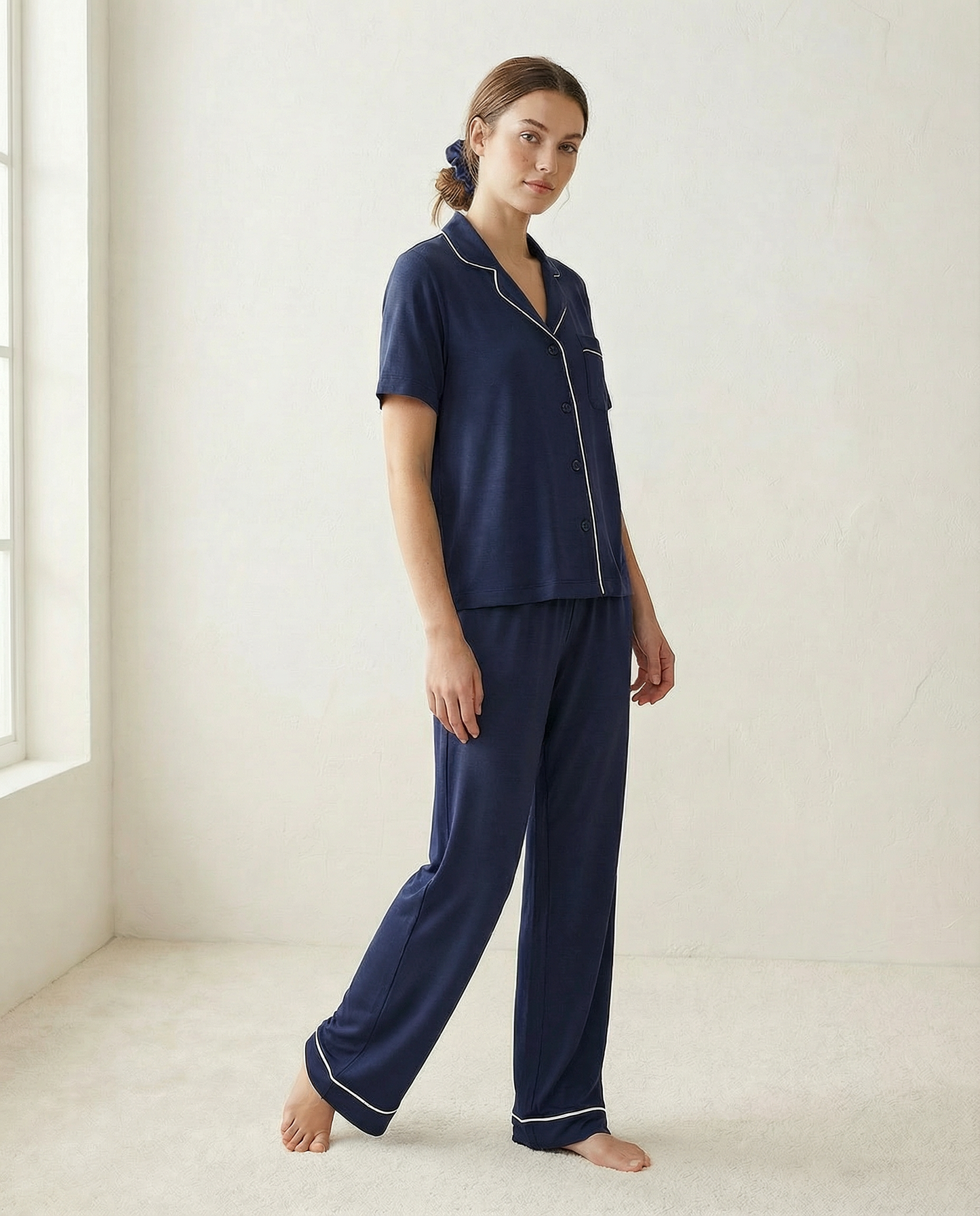 Woman wearing navy blue pajamas in a minimalistic room.