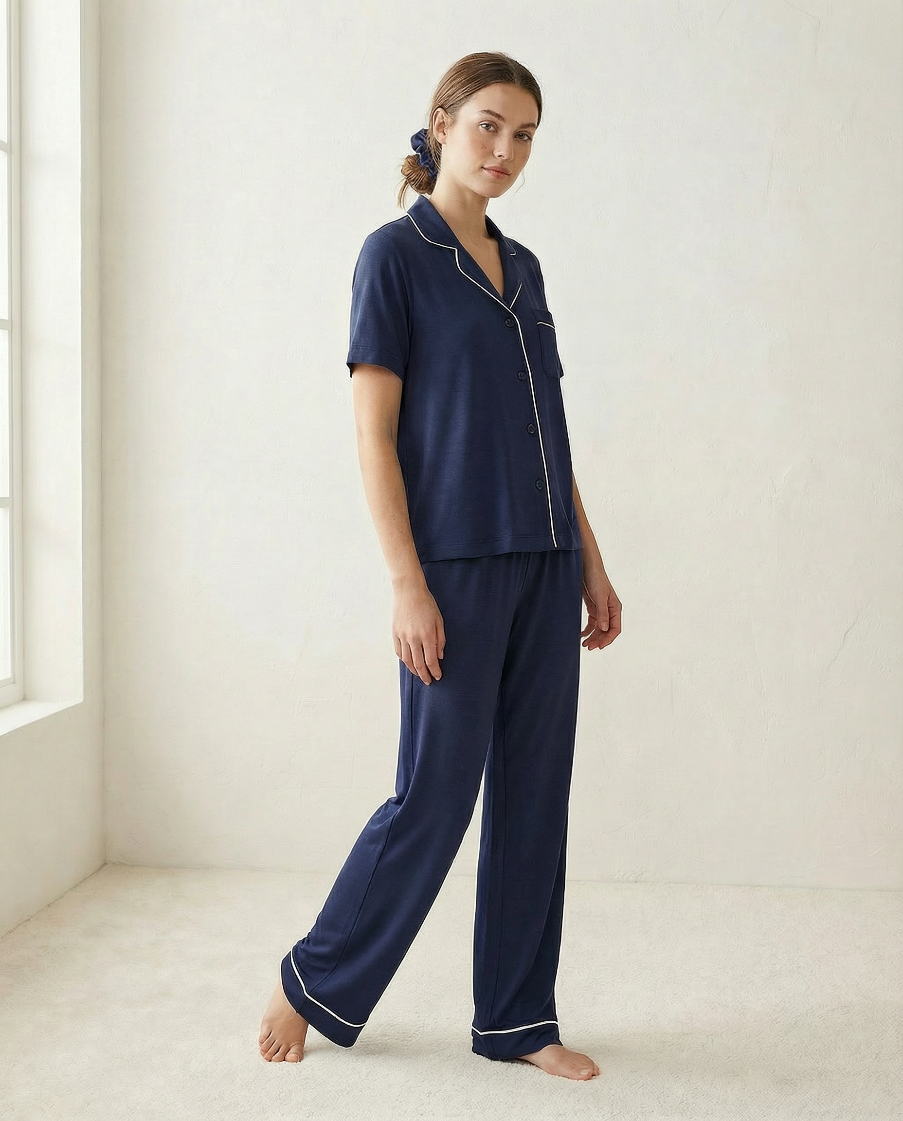 Woman wearing navy blue pajamas in a minimalistic room.