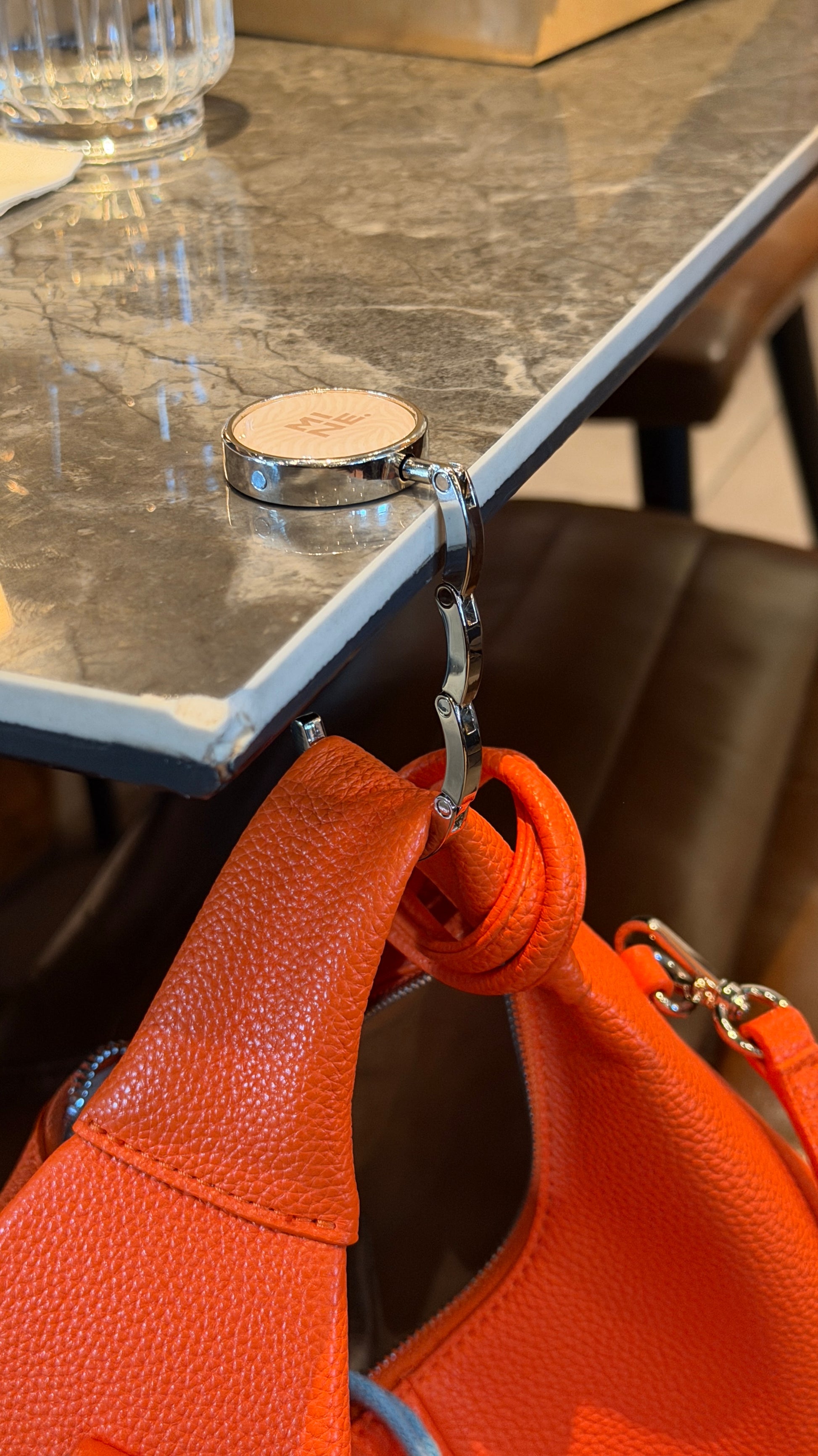 Orange handbag with a metal clasp on a marble surface