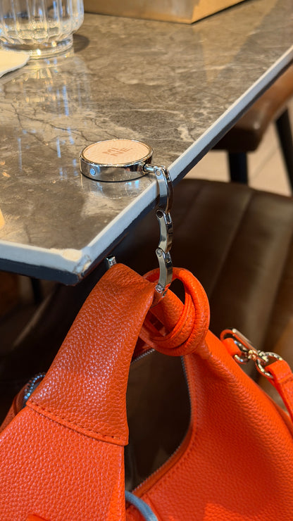 Orange handbag with a metal clasp on a marble surface